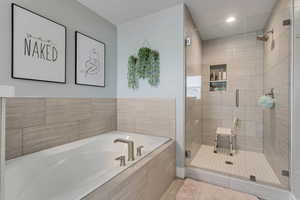 Bathroom featuring a garden tub, a shower stall, and recessed lighting