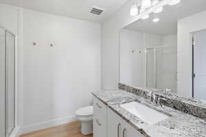 Primary Bathroom with a stall shower, vanity, and light wood-type flooring