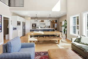 Living room with light wood finished floors, a high ceiling, and recessed lighting