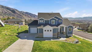Craftsman house with board and batten siding, a mountain view, stone siding, driveway, and a front yard