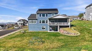 Back of property with a patio area, a residential view, a mountain view, a yard, and solar panels