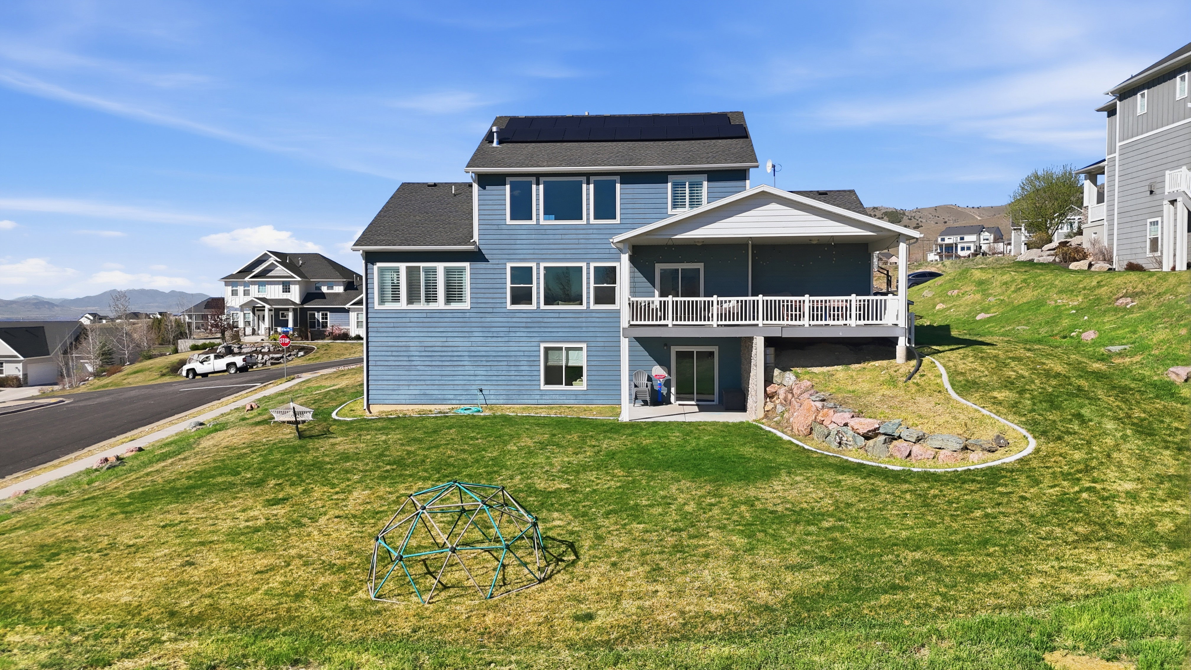 Two-story residence featuring blue siding, a dark roof, and multiple windows