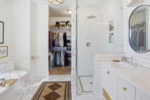 Bathroom with a spacious closet, vanity, and a stall shower