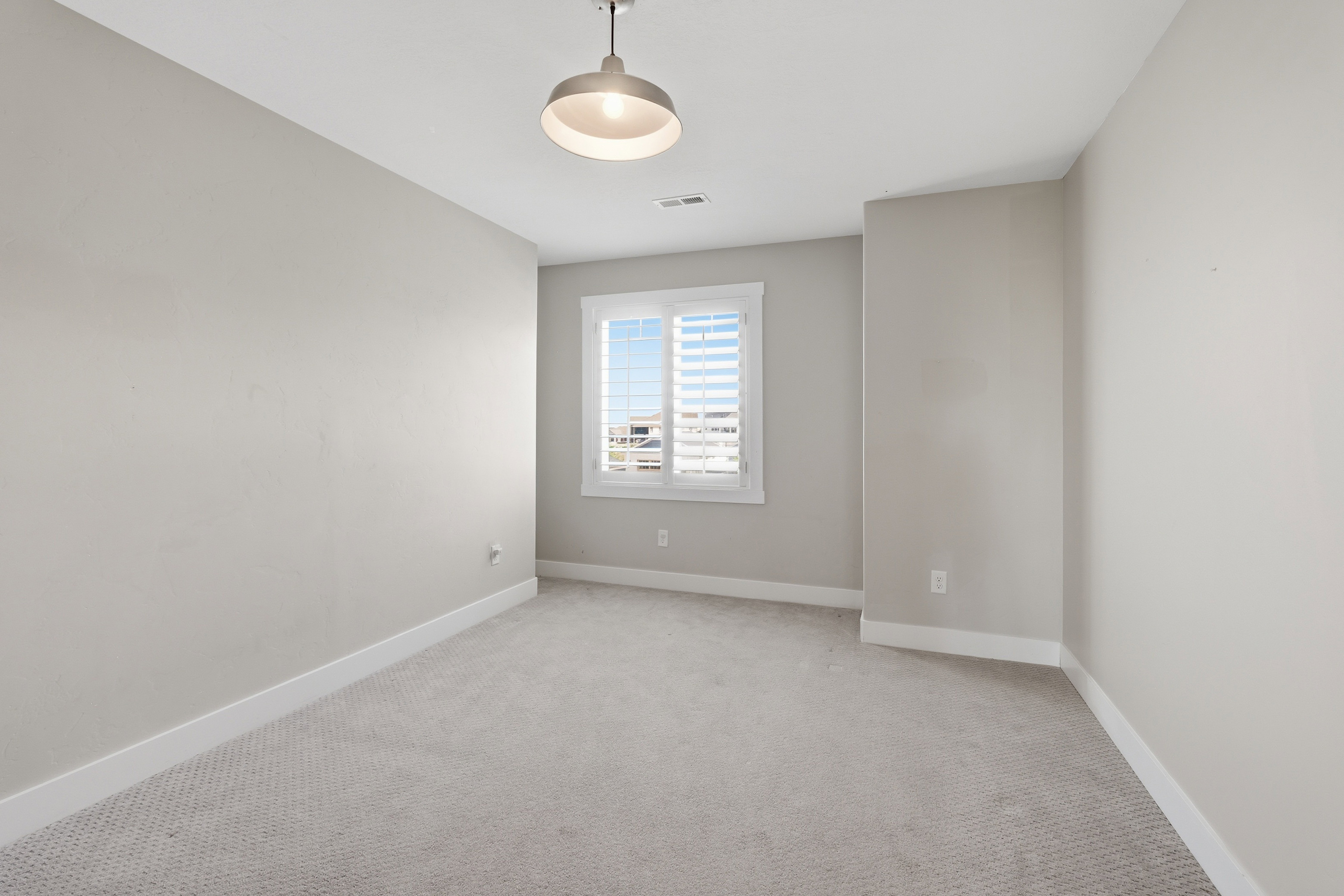 Carpeted room with a central ceiling light fixture, neutral wall paint, and white trim molding