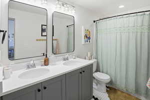 Bathroom with double vanity, a shower with shower curtain, and recessed lighting