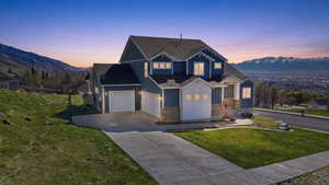 View of front facade featuring a lawn, driveway, a mountain view, board and batten siding, and a shingled roof