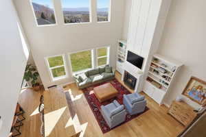 Living room featuring a high ceiling, light wood-style floors, and a large fireplace