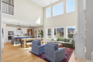 Living room featuring light wood-style flooring, recessed lighting, plenty of natural light, and a high ceiling