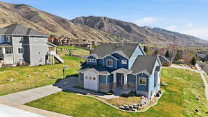 View of front of home featuring stone siding, a garage, driveway, a mountain view, and a residential view