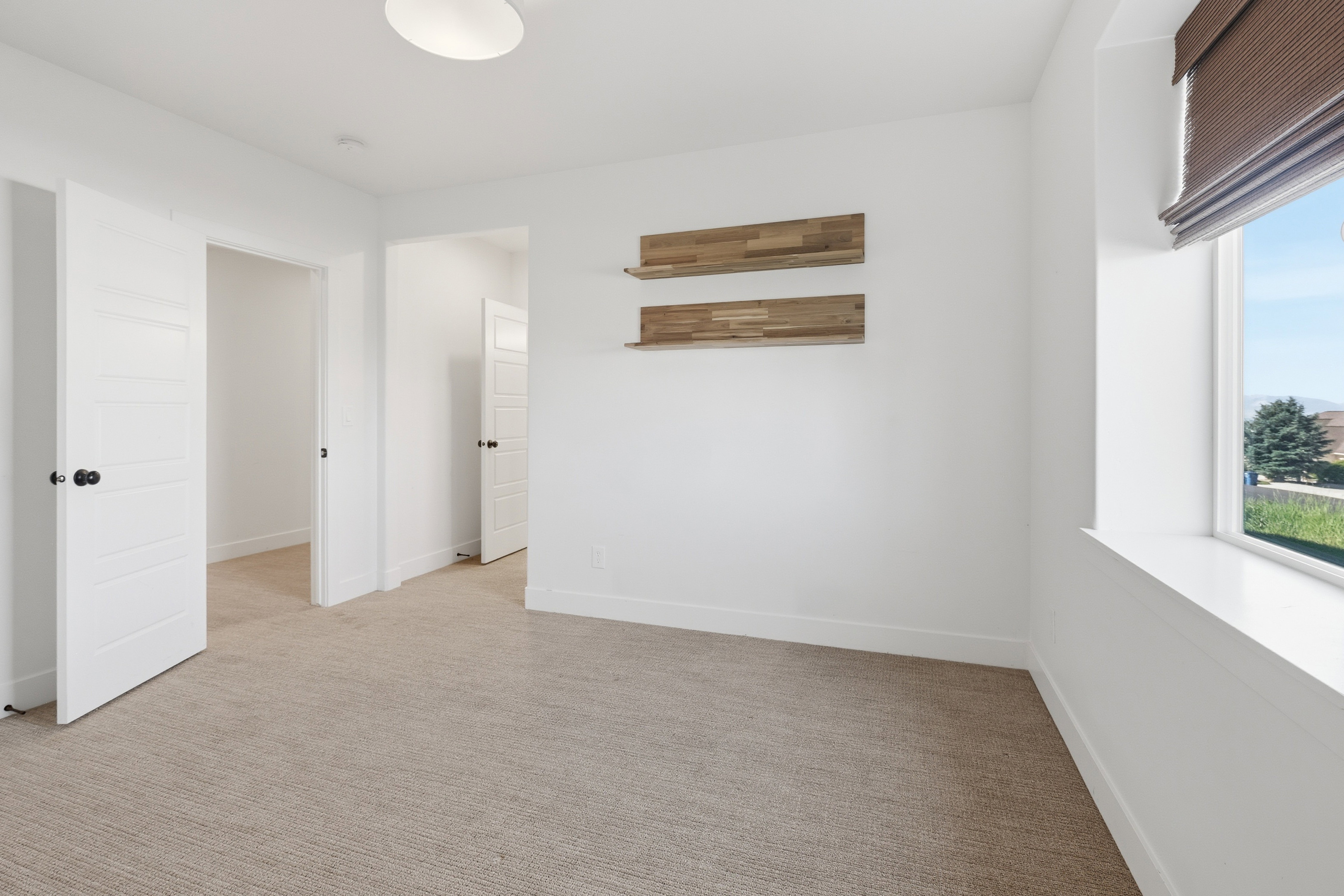 Neutral-toned carpeting extends throughout this interior space, featuring bright white walls and trim