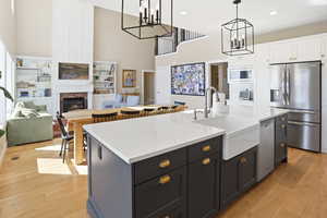 Kitchen with an island with sink, stainless steel appliances, a high ceiling, two tone cabinets, and open floor plan