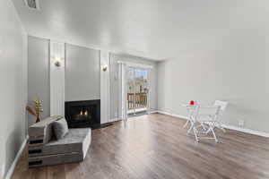 Living area with a warm lit fireplace and wood-type flooring