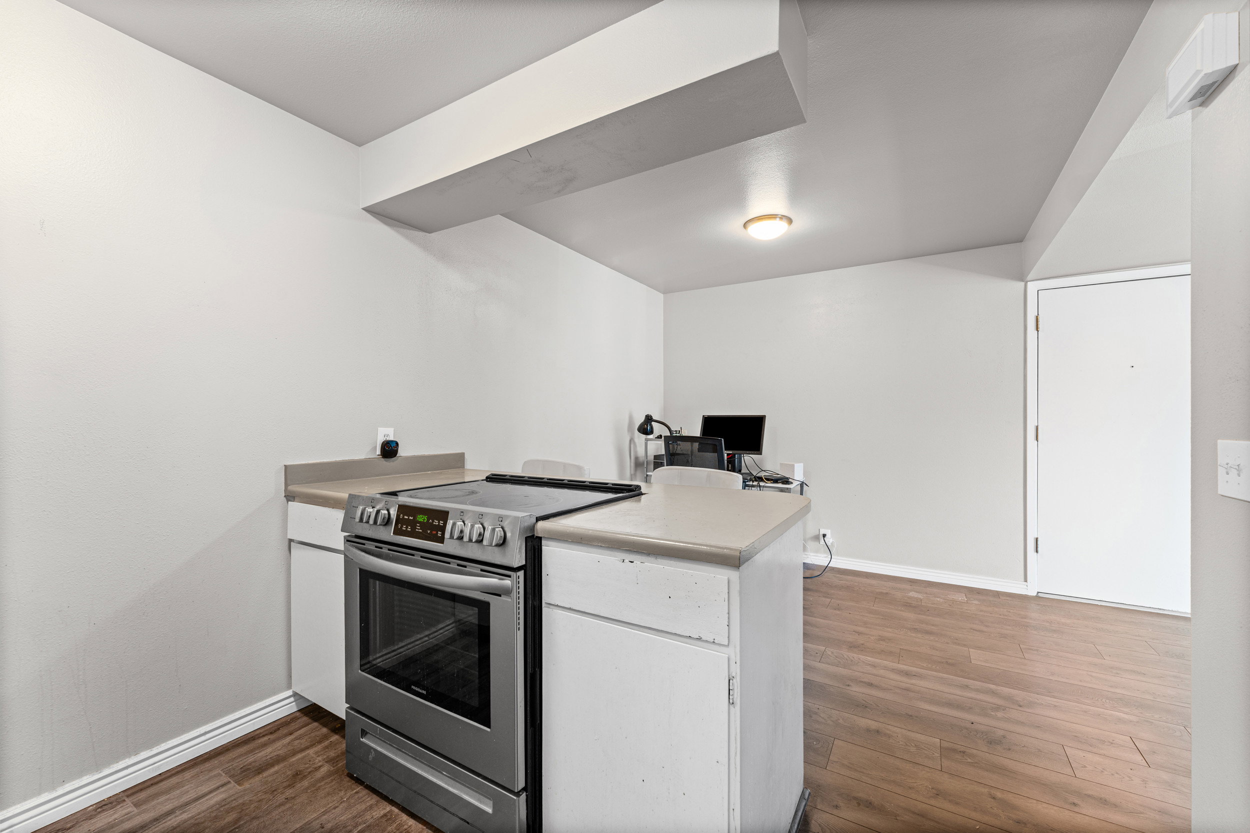 Kitchen featuring stainless steel electric stove, white cabinets, light countertops, a peninsula, and an office area