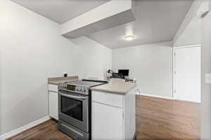 Kitchen featuring stainless steel electric stove, white cabinets, light countertops, a peninsula, and an office area