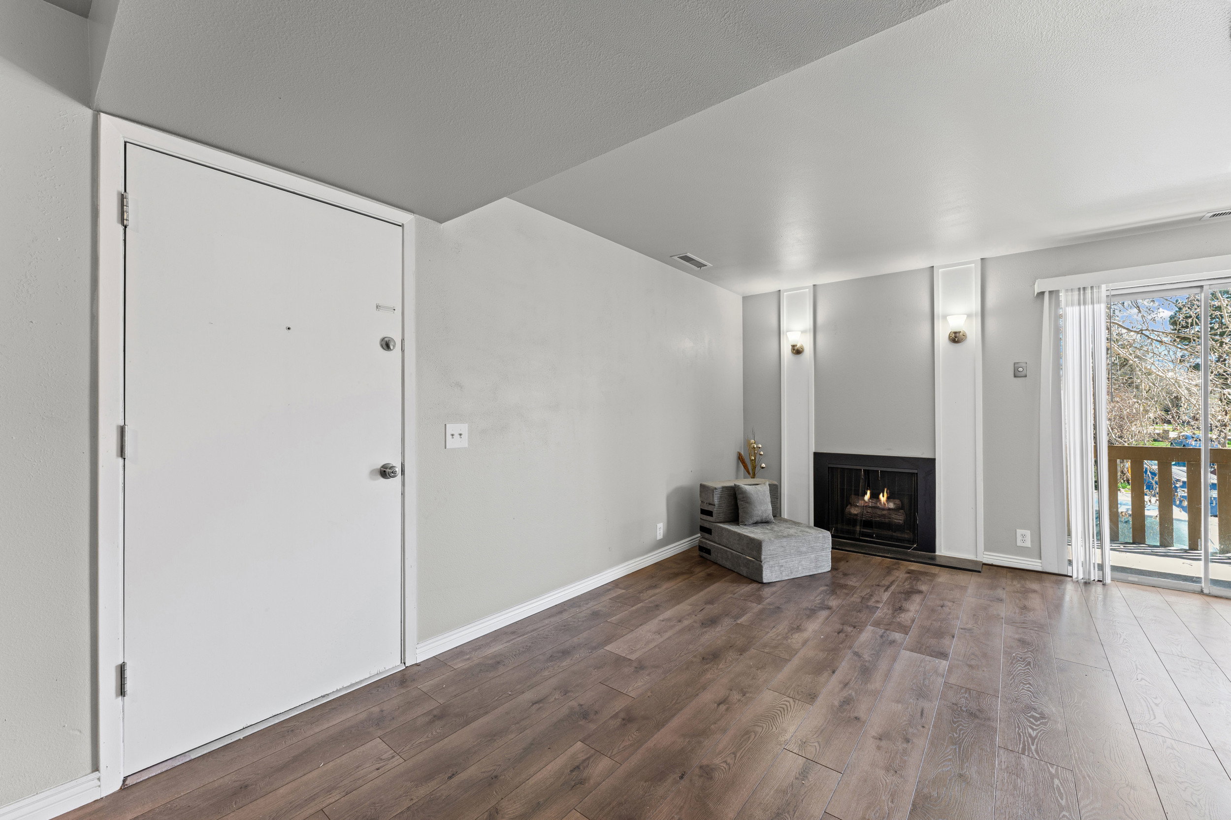 Unfurnished living room featuring a warm lit fireplace and dark wood-style flooring