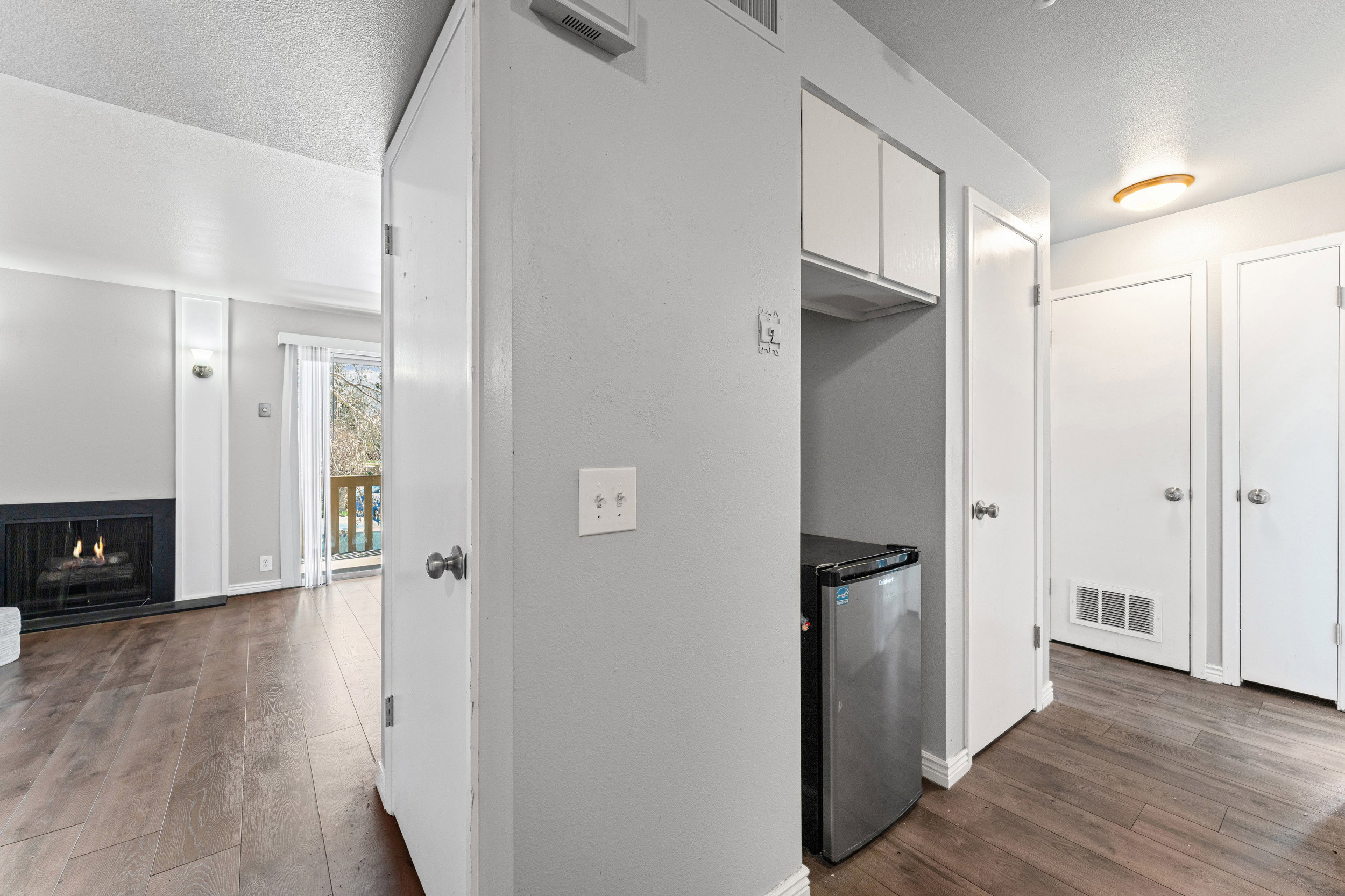 Kitchen featuring dark wood-style flooring, fridge, a lit fireplace, and white cabinets