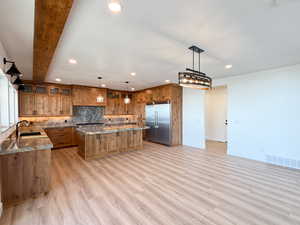 Kitchen featuring a kitchen island, wood finish cabinets, decorative backsplash, and built in fridge