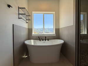 Full bath with a soaking tub, tile patterned flooring, and wainscoting