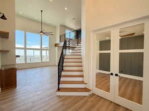Stairway featuring ceiling fan, a high ceiling, wood finished floors, and recessed lighting
