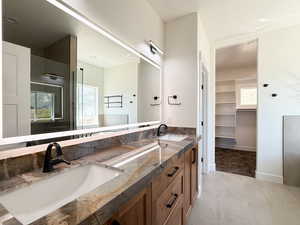 Full bath featuring double vanity, a spacious closet, light tile patterned flooring, and walk in shower