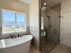 Bathroom with a freestanding tub, a shower stall, a mountain view, wainscoting, and recessed lighting