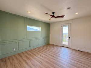 Unfurnished room featuring a decorative wall, light wood-style floors, a textured ceiling, a ceiling fan, and recessed lighting