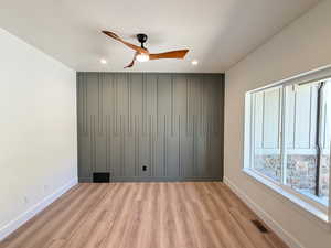 Unfurnished bedroom featuring light wood-style flooring, ceiling fan, recessed lighting, and an accent wall
