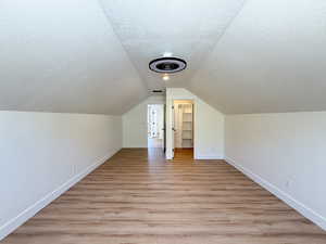 Bonus room with a textured ceiling and light wood-style floors