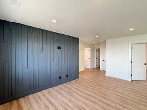 Unfurnished living room featuring light wood-style flooring, recessed lighting, and a textured ceiling
