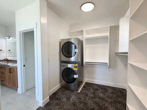 Laundry area with stacked washer and clothes dryer and baseboards