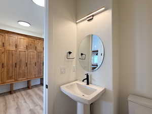 Half bath with toilet and light wood finished floors
