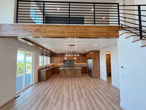 Kitchen with a center island, wood finish cabinetry, glass fronted cabinets, decorative light fixtures, and a high ceiling