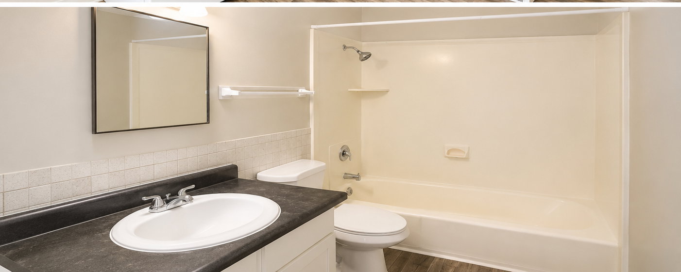 Bathroom featuring a single vanity with a dark countertop, white drop-in sink, and chrome faucet