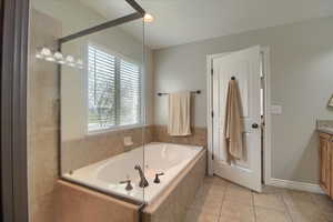 Full bath featuring vanity, a jetted tub, light tile patterned floors, and recessed lighting