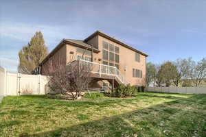 Back of property featuring a fenced backyard, a gate, a wooden deck, and stucco siding
