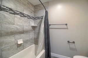 Full bath with shower / bath combination with curtain and toilet