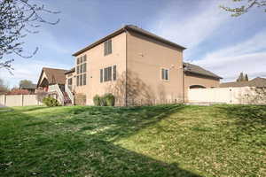 Back of house with a fenced backyard and stucco siding