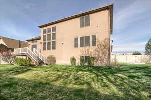 Rear view of property featuring stucco siding and a wooden deck