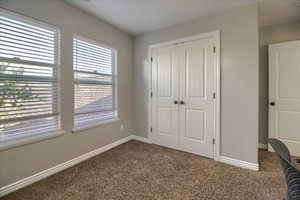 Unfurnished bedroom featuring dark colored carpet and a closet