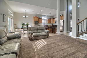 Living room featuring light carpet, a chandelier, and a high ceiling