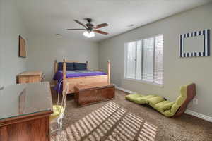 Carpeted bedroom with ceiling fan and baseboards