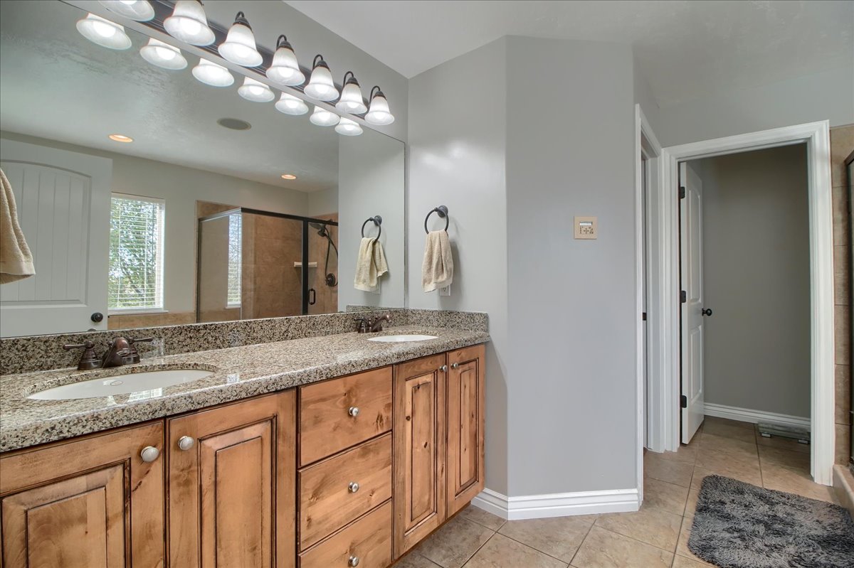 Bathroom with double vanity, a shower stall, and light tile patterned flooring