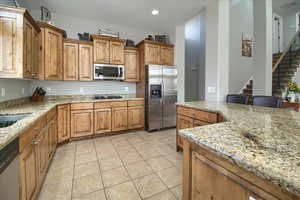 Kitchen featuring wood finish cabinets, stainless steel appliances, light stone counters, and recessed lighting