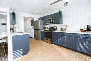 Kitchen featuring stainless steel appliances, tasteful backsplash, a breakfast bar, blue cabinetry, and recessed lighting