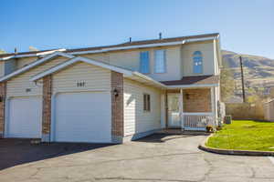 Traditional-style house featuring brick siding, covered porch, a front yard, driveway, and a shingled roof