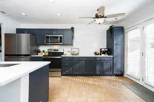 Kitchen featuring stainless steel appliances, backsplash, a ceiling fan, light tile patterned floors, and recessed lighting