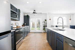 Kitchen featuring stainless steel appliances, tasteful backsplash, light tile patterned floors, light stone countertops, and recessed lighting