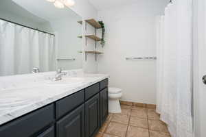 Bathroom featuring curtained shower, vanity, and light tile patterned floors