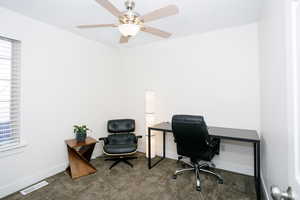 Carpeted office with healthy amount of natural light and a ceiling fan