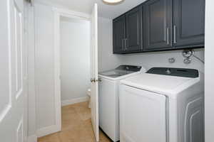 Laundry room featuring washer and clothes dryer, light tile patterned floors, and cabinet space